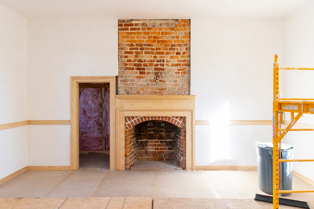 Brick fireplace in an empty room with white walls